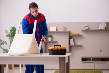 Young male contractor repairing chair indoors