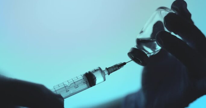 Doctor wearing protective gloves holding a syringe and preparing for covid 19 or other vaccine injection.