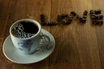 Coffee Cup and Word Love Written with Coffee Beans on Wooden Table