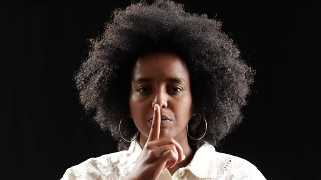 finger on lips closeup portrait of beautiful black woman