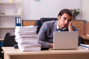 Young male employee unhappy with excessive work in the office