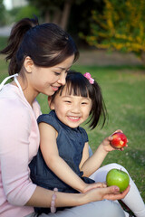 Fototapeta premium Mother eating fruit outdoors with her Girls