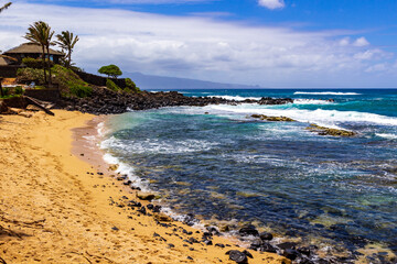 Sun covered beach with rocky shoreline in Maui, Hawaii