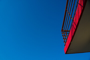 Photo of a bright red roof railing with contrasting  clear blue sky.