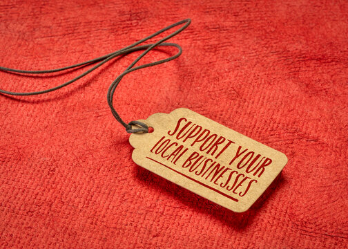 support your local businesses - a paper price tag with a twine against red handmade paper, local shopping