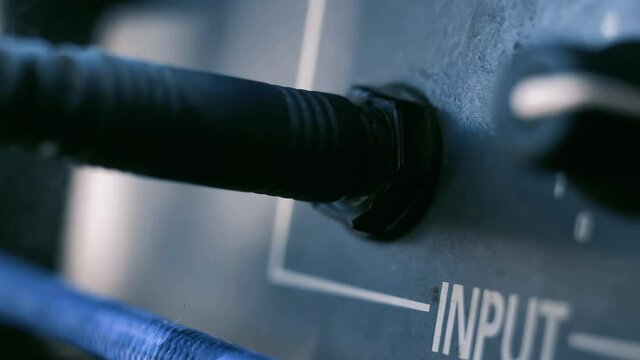 Man Hand connecting Jack Audio plug-in into the Guitar Amplifier Outdoors. Close Up. 4K Resolution.