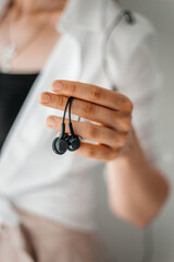 Close up of women's hands holding headphone, woman in the office using mobile phone during coffee break. Selective Focus