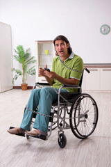 Young male invalid in wheel-chair suffering at home