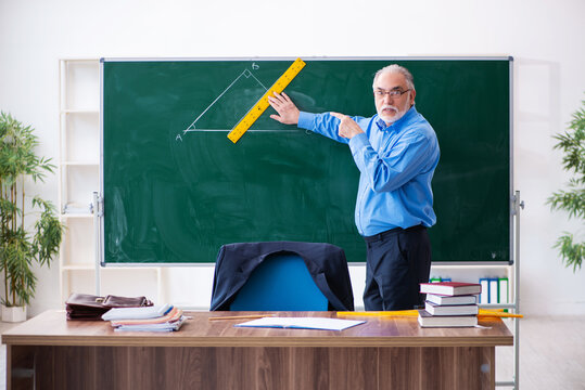 Old male geometry teacher holding triangle