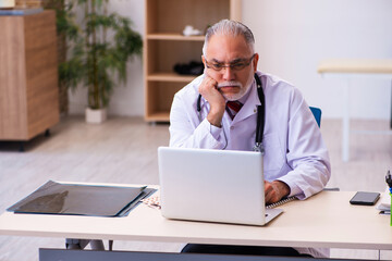 Old male doctor working in the clinic