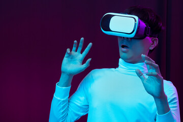 Excited asian young man wearing VR headset in neon light, Future technology concept.