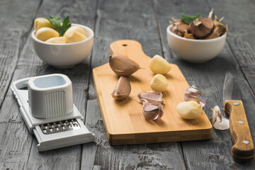 Knife, grater and dill slices on a cutting board on a wooden table.