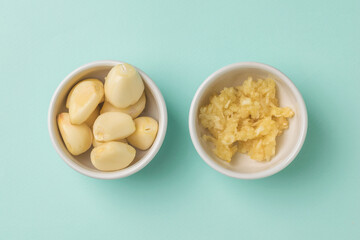 Garlic cloves and mashed garlic in white bowls on a blue background.