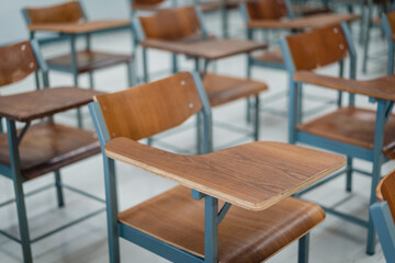 Fototapeta na wymiar Empty university classroom with many wooden chairs. Wooden chairs well arranged in college classroom. Empty classroom with vintage tone wooden chairs. Back to school concept.