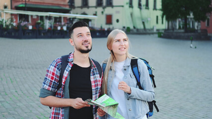 Man and woman tourists with map looking for new historical place in city center. They finding something interesting.