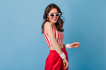 Young lady in gold earrings is smiling. 80s style woman in red and white outfit posing on isolated background