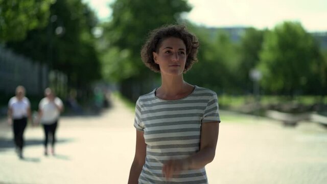 curly haired woman going for a walk in a public park