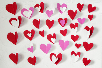 Red, white and pink paper hearts cut out of paper for decorating on Valentine's Day on a white table. Valentine's Day concept