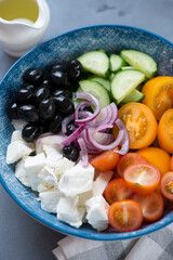 Bowl of greek salad with tomatoes, cucumber, olives, red onion and chunks of feta cheese, vertical shot, close-up, selective focus