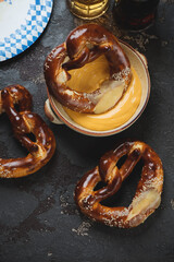 Cheese dip, german pretzels and beer, high angle view over brown stone background, vertical shot