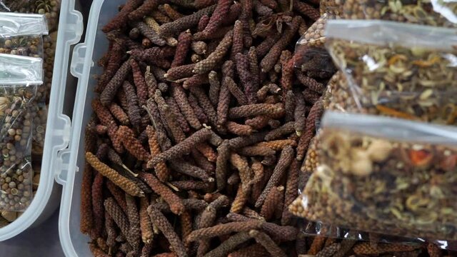 Dried Long pepper or Piper longum heap of pippali in a box and plastic bag prepared for sale at the rural food market in northern Thailand.