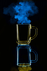 Just a glass on a black background with a reflection. Blue and yellow, with steam.