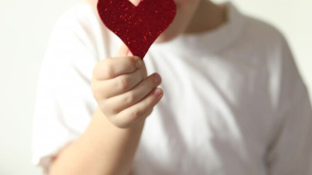 Red heart close up in hands of little kid boy  on Valentines Day.