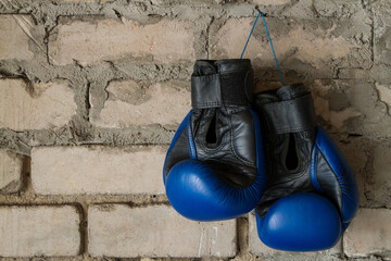 A pair of leather boxing gloves. Sports equipment on a brick wall background.