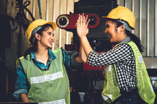 Two factory job worker celebrate success together in the manufacturing workshop or warehouse . Industry work achievement concept .