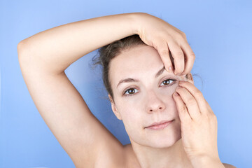 Naklejka premium Beautiful smiling woman doing facial exercises, face fitness, self-massage against wrinkles and old age.