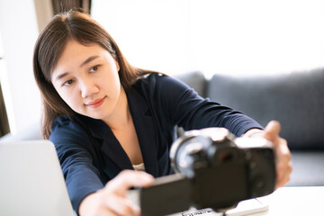 Happy Asian woman setting up and preparing a video camera for making a live steaming video online