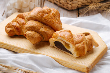 Closeup on french croissants with chocolate filling on the wooden cutting board