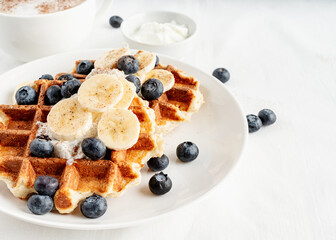 High angle view of fresh made waffles with blueberries, banana and yoghurt