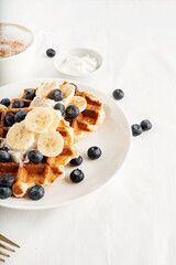 High angle view of fresh made waffles with blueberries, banana and yoghurt