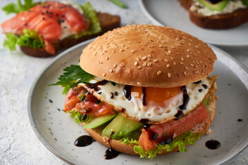 Tasty homemade sandwich with salmon , fried egg ,herbs and avocado