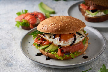 Tasty homemade sandwich with salmon , fried egg ,herbs and avocado