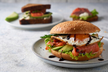 Tasty homemade sandwich with salmon , fried egg ,herbs and avocado