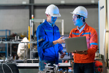 Male Asian engineer professional  having a discussion standing concult cnc machine in the factory ,two asian coworker brainstorm  explaining and solves the process of the cnc operate machine