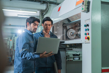 Fototapeta premium Male Asian caucasian engineer professional having a discussion standing consult at machine in the factory ,two expert coworker brainstorm explaining and solves the process of the cnc operate machine