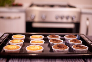 Cupcakes on a baking sheet on the table against the background of home kitchen.