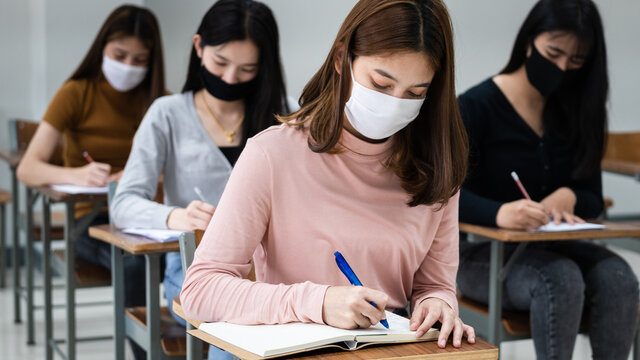 Female Teenager College Students Wears Face Mask And Keep Distance While Studying In Classroom And College Campus To Prevent COVID-19 Pandemic