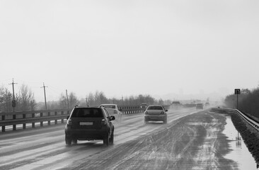 The movement of cars on a wet road towards the city