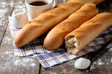 Closeup on several french baguettes with coffee and milk on the wooden decorated table