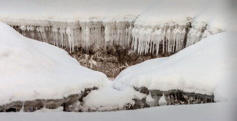Icicles and frost on a snow-covered frozen river