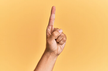 Arm and hand of caucasian man over yellow isolated background counting number one using index...