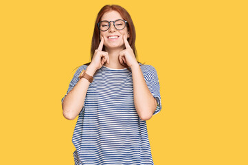 Young read head woman wearing casual clothes and glasses smiling with open mouth, fingers pointing and forcing cheerful smile