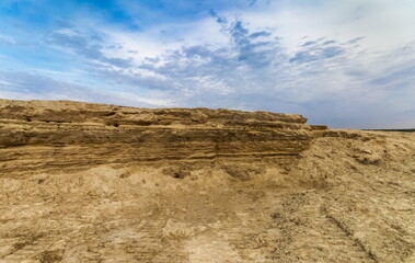 Sand ledge with holes swallows nests on the background of blue sky with clouds