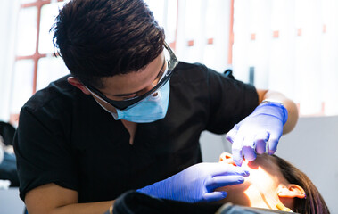 Obraz na płótnie Canvas Men dentist wearing protective face mask examining a patient