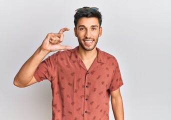 Young handsome man wearing casual summer clothes smiling and confident gesturing with hand doing small size sign with fingers looking and the camera. measure concept.