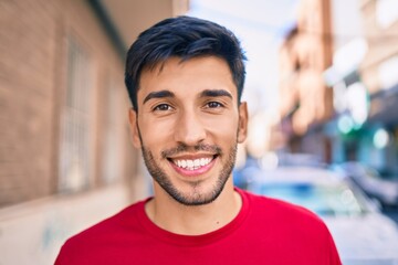 Young latin man smiling happy walking at the city.